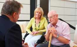 elderly man and woman sitting and talking to a business man